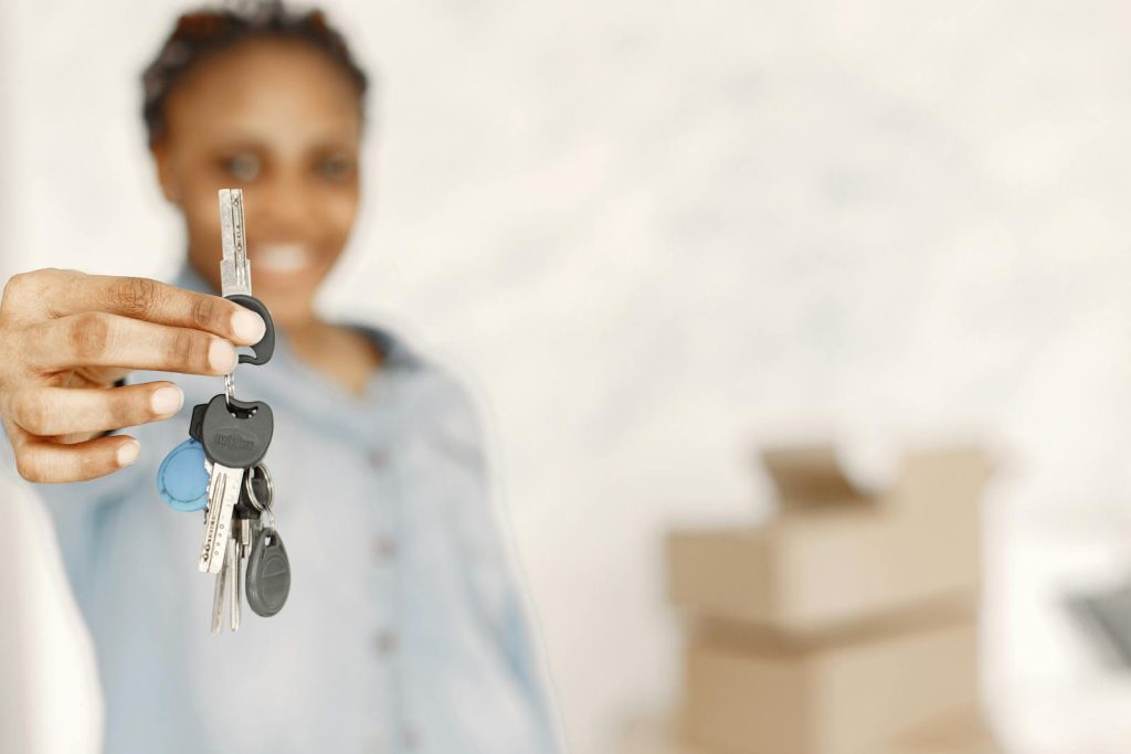 Close-up of a woman holding keys with a blurred background, symbolizing a new home or real estate concept.